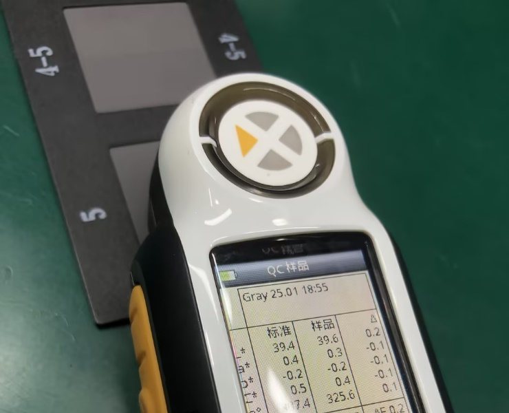 A handheld colour-difference meter on a bench, with its measurement head and readout screen visible