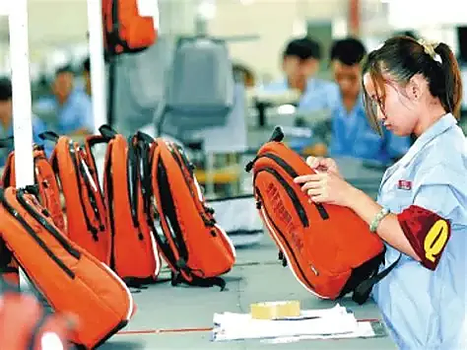 QC inspector checking a finished bag at her station, checklist on the bench